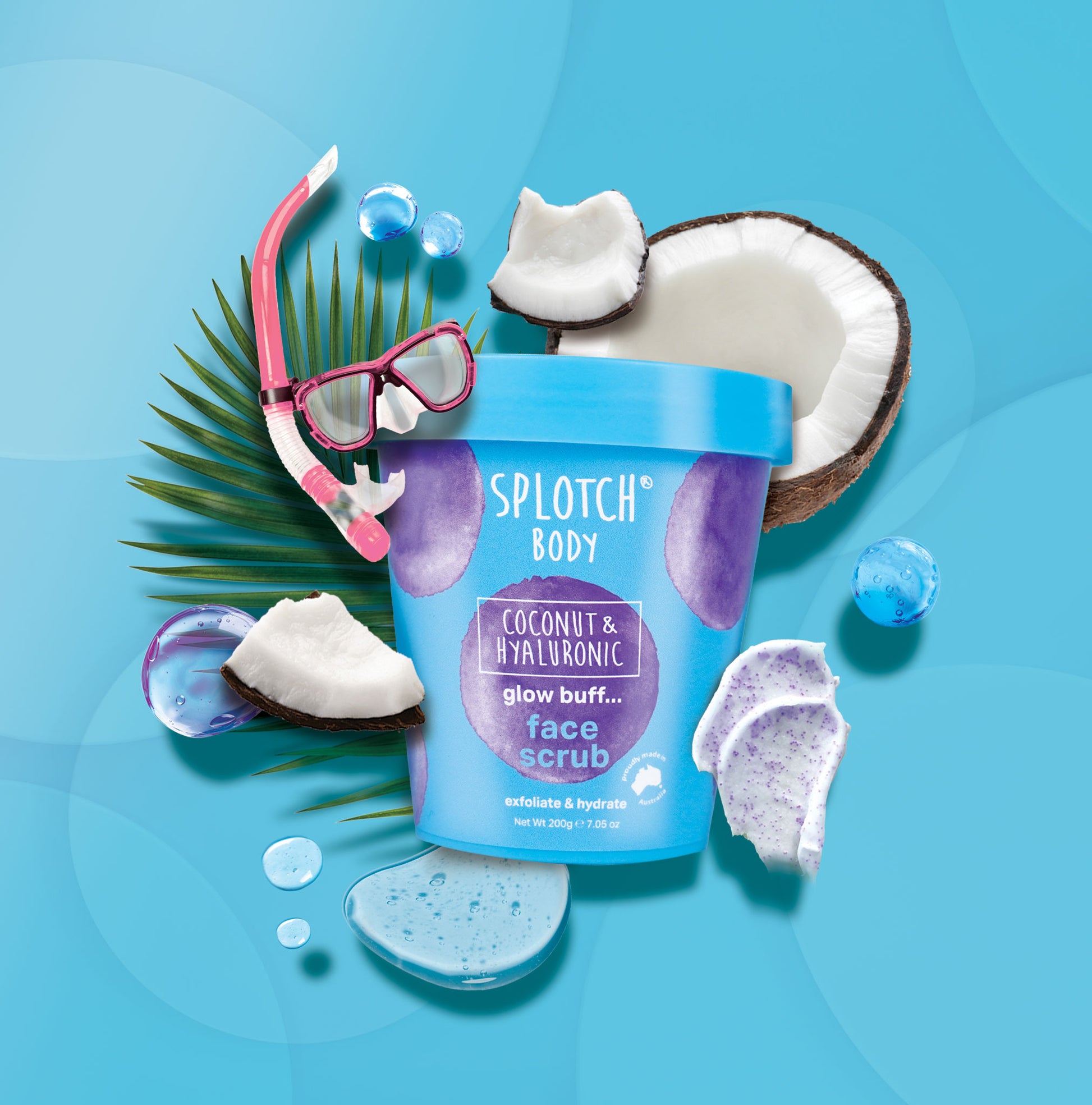 A clear, blue, and purple tub of "Splotch Body" "Coconut & Hyaluronic glow buff... face scrub" surrounded by coconut pieces and a snorkeling mask. The scrub is meant to "exfoliate & hydrate" with a small seal that reads "proudly made in Australia".