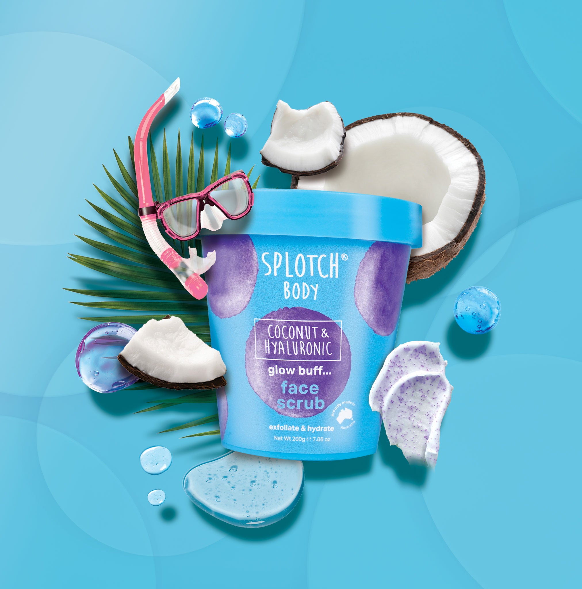 A clear, blue, and purple tub of "Splotch Body" "Coconut & Hyaluronic glow buff... face scrub" surrounded by coconut pieces and a snorkeling mask. The scrub is meant to "exfoliate & hydrate" with a small seal that reads "proudly made in Australia".
