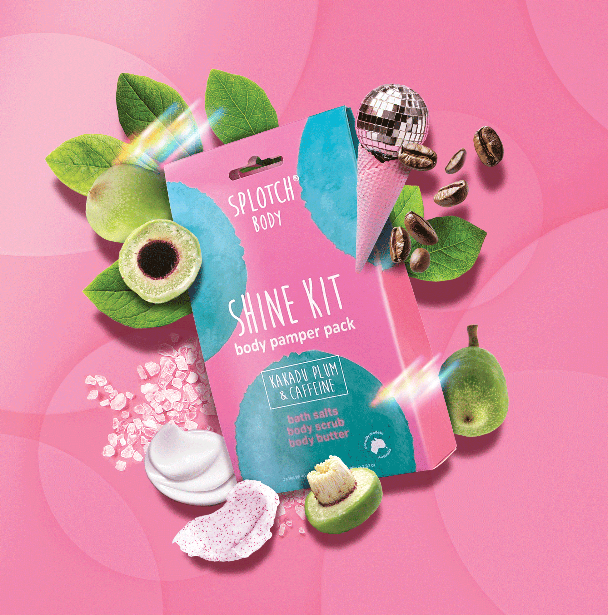 
A marketing product shot for the SPLOTCH BODY SHINE KIT body pamper pack featuring a pink and teal pouch on a pink background. The pouch is labeled "KAKADU PLUM & CAFFEINE" and contains bath salts, body scrub, and body butter.